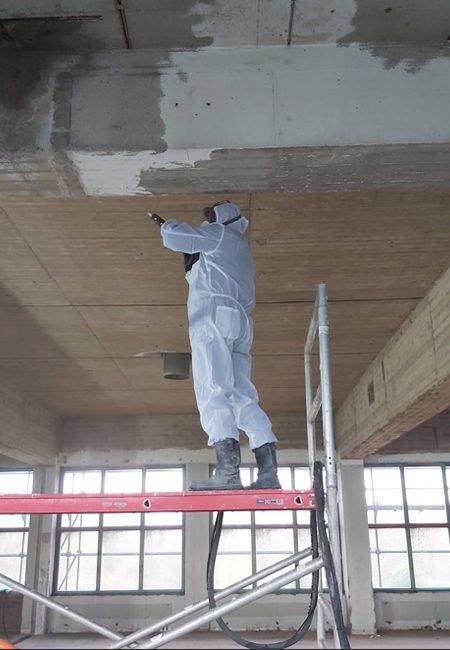 Medewerker straalt betonnen wanden en plafonds vanaf een rolsteiger bij SugarCity