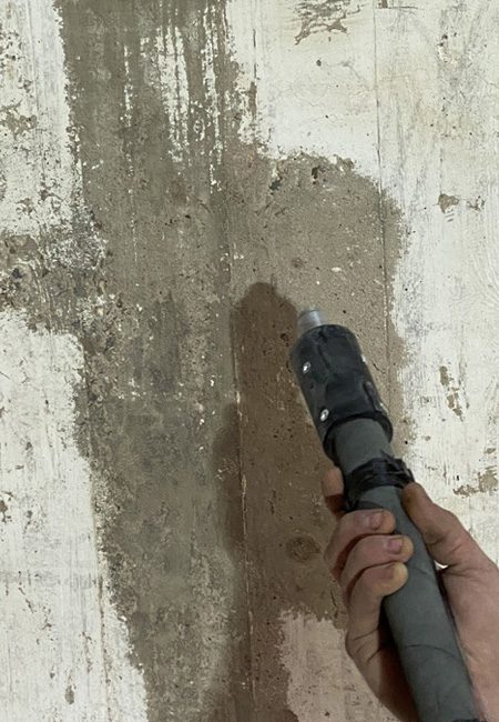 Detail van het stralen van een betonnen wand om een bestaande coating te verwijderen