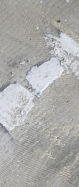 Detail van hardnekkige lijmresten op een betonnen vloer