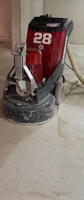 Detail van dezelfde betonvloer tijdens de machinale schuurbehandeling