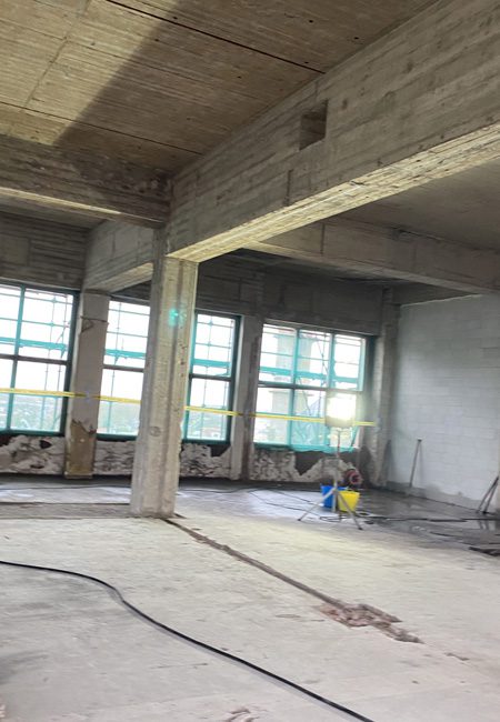 Kaalgestraalde betonnen wanden en plafonds in de fabriekshal van SugarCity