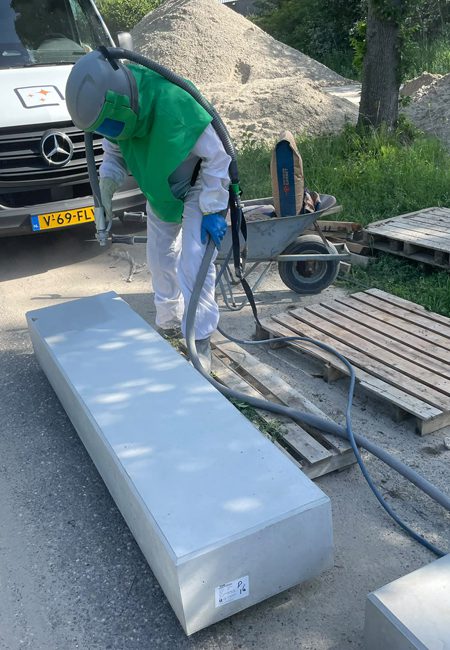 Prefab betonelement opruwen Medewerker straalt het loopvlak en de zichtzijde van een prefab betonnen traptrede