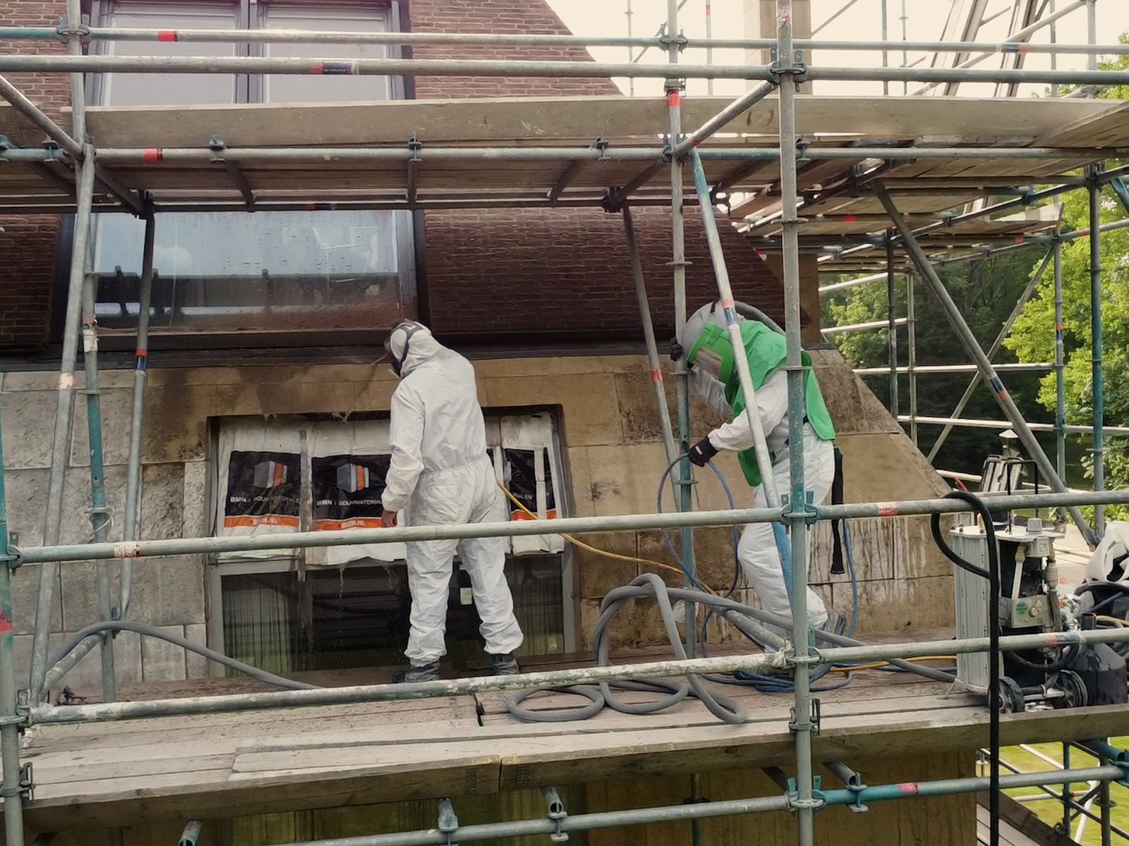 Medewerkers op steiger bij kalkstenen buitengevel